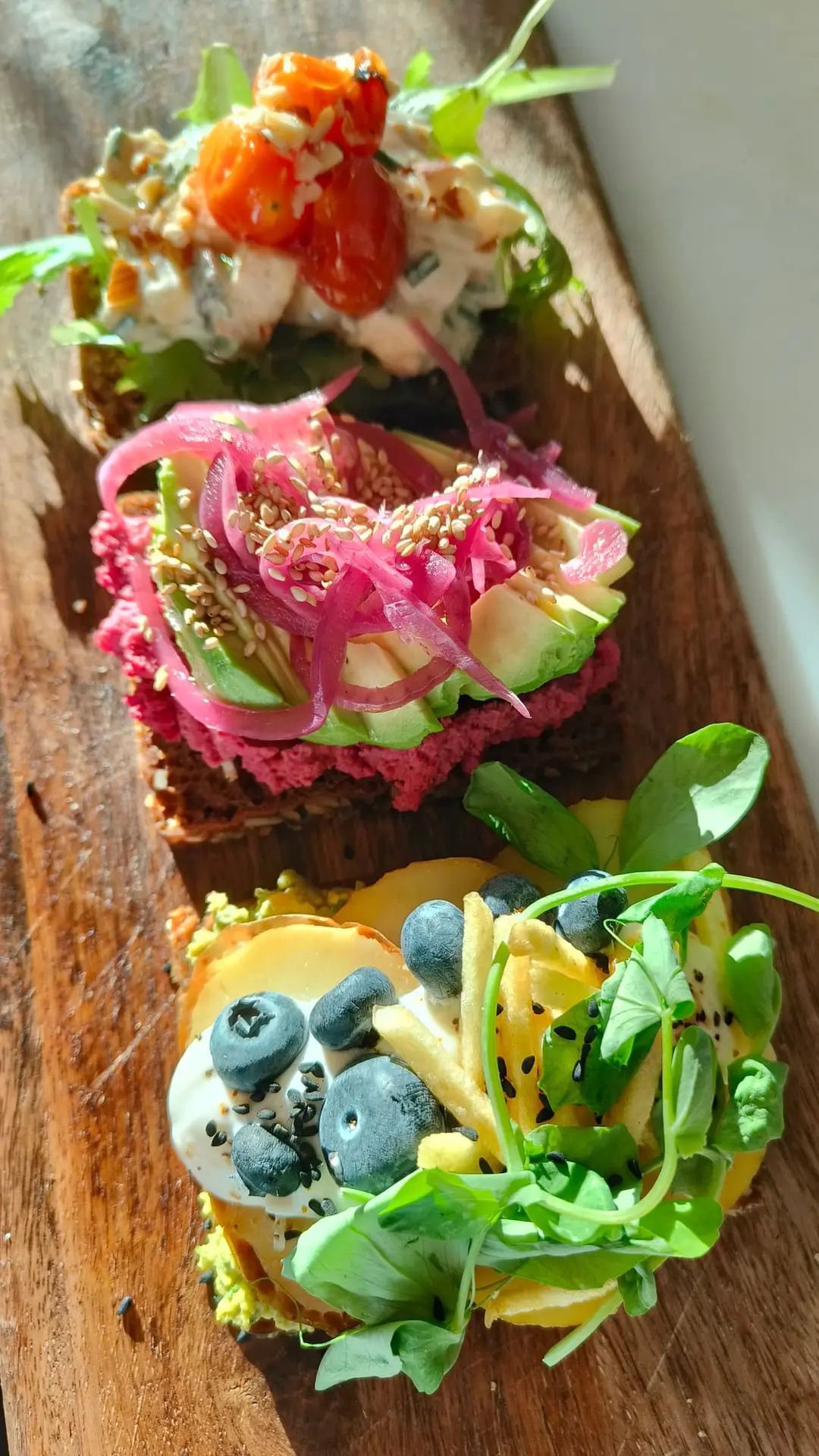 Farverigt plantebaseret smørrebrød på træbræt hos The Break Café